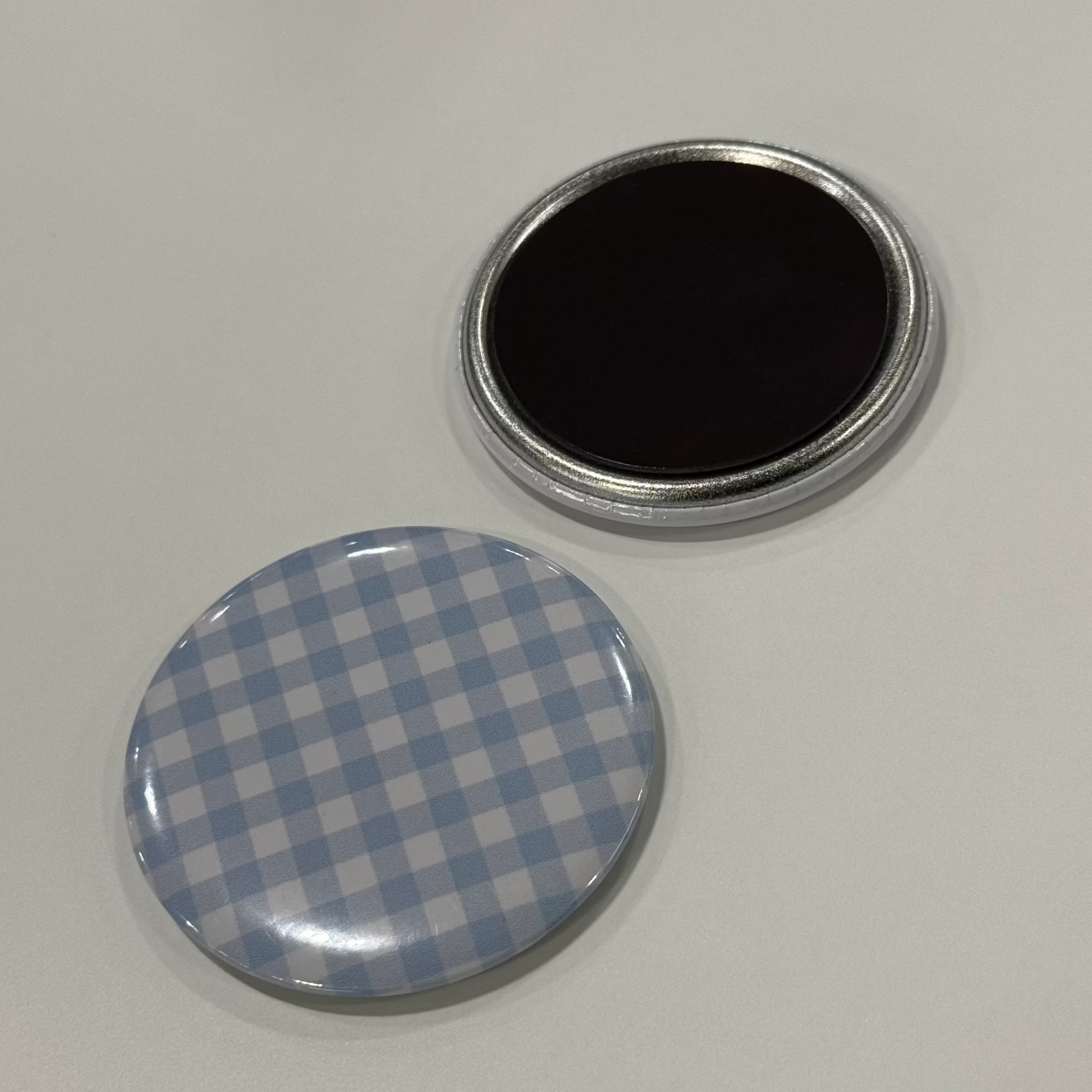 Two circular objects, one checkered and one solid black, on a fridge